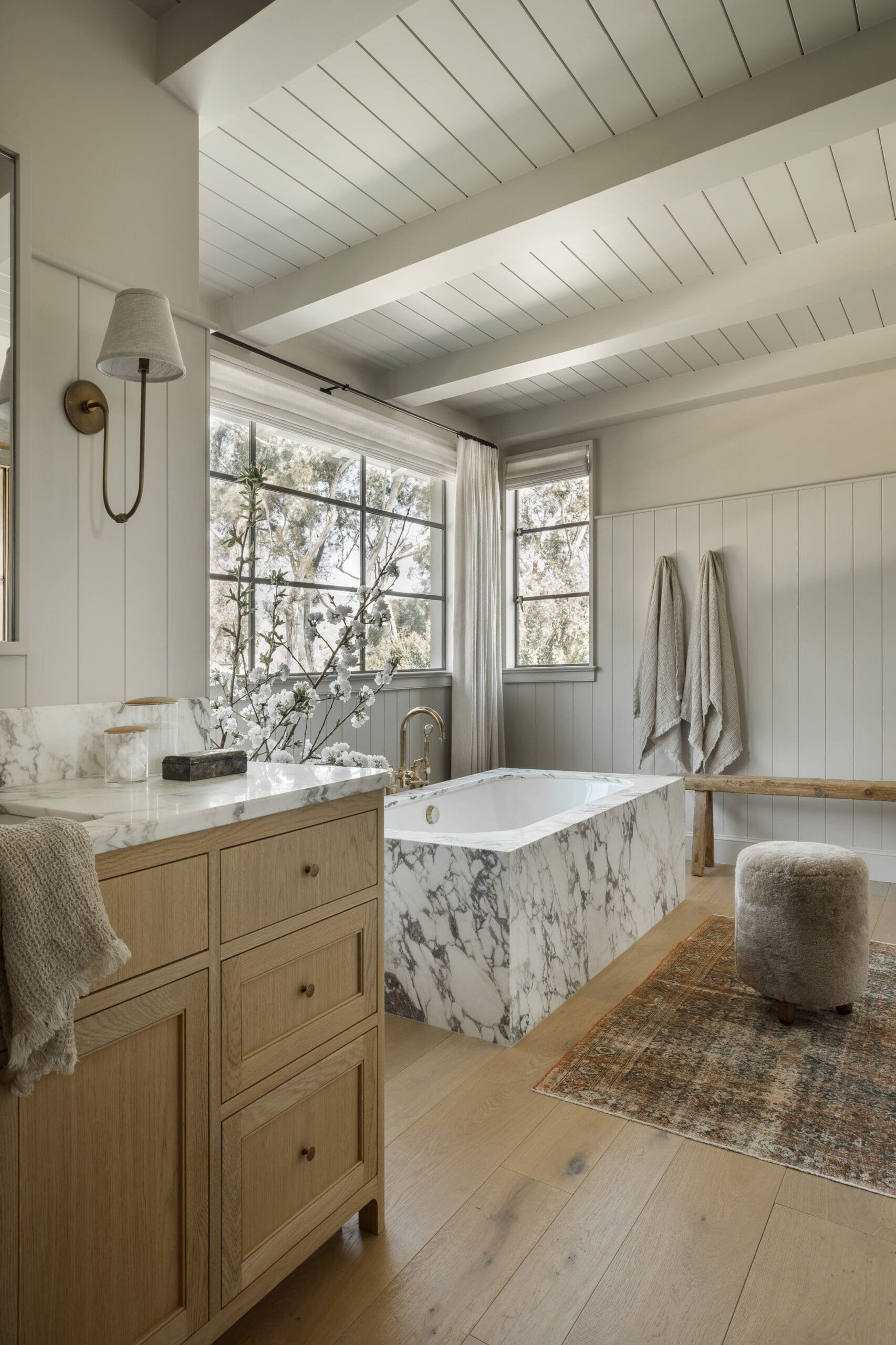 719 Amalfi: marble bath and oak vanity beneath a white timber-beamed ceiling.