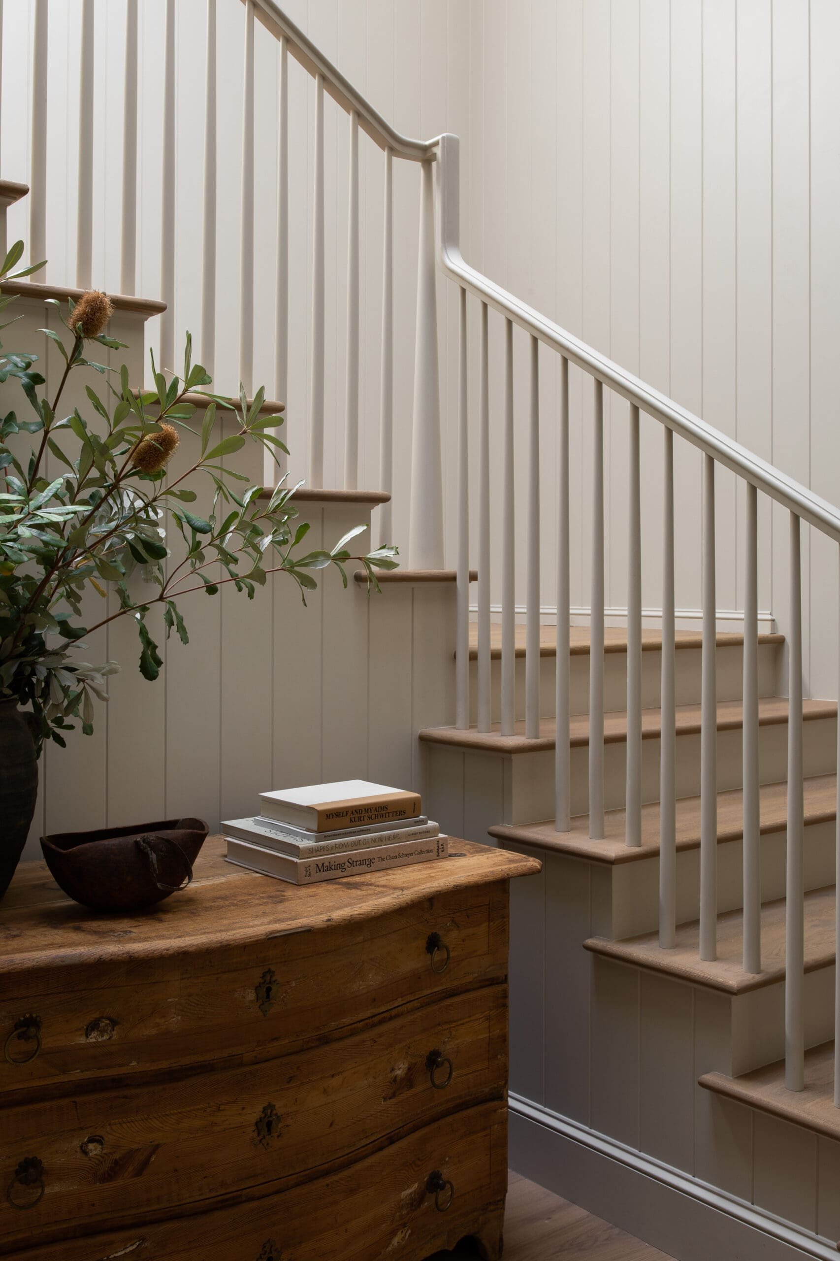 719 Amalfi: curved stair railing, timber treads and an antique chest against ivory paneling.